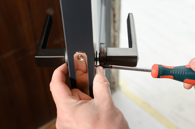 A man installs a doorknob in a door, carpentry at home.